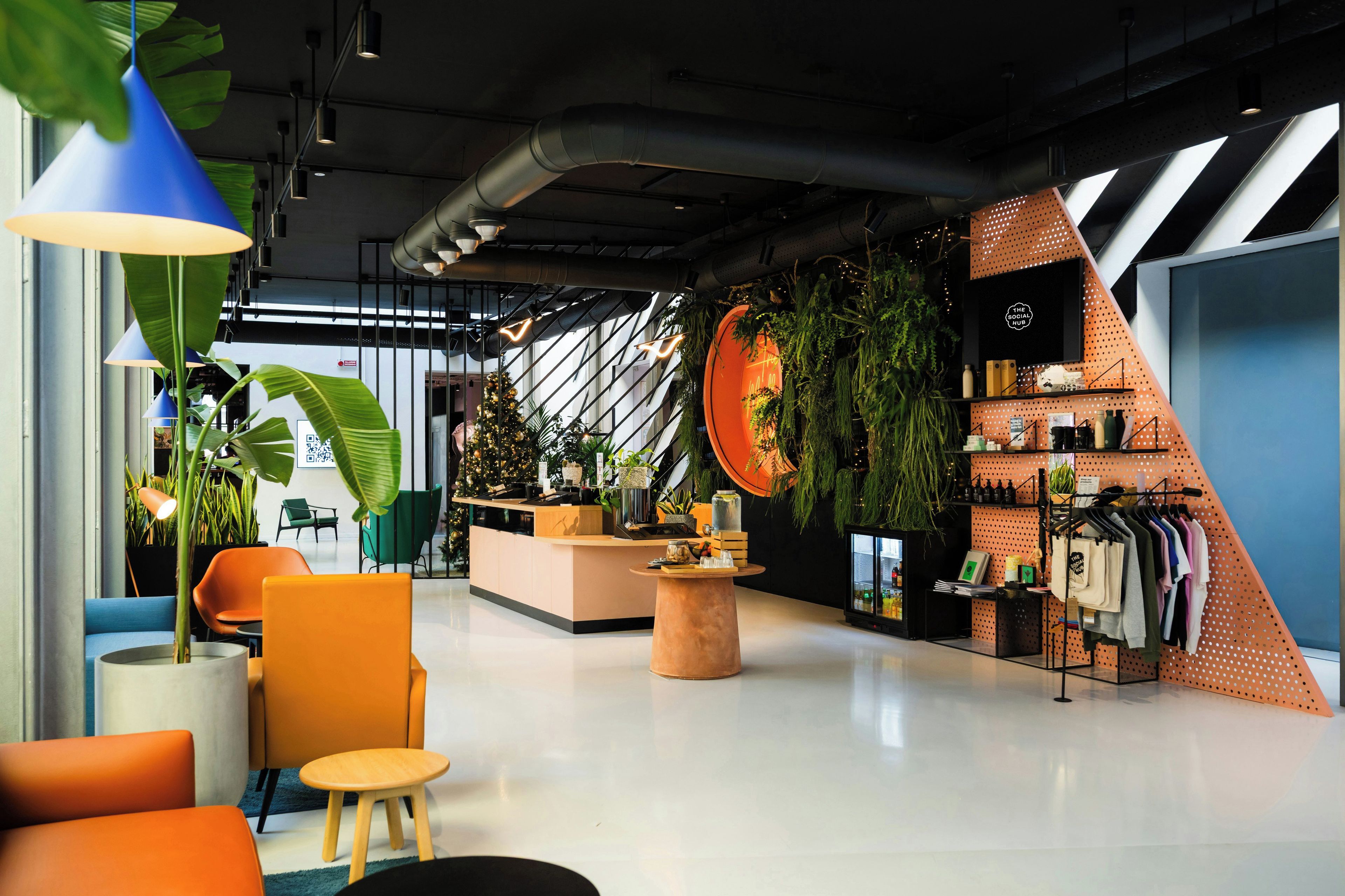 A modern interior with a reception desk, seating area, and a clothing rack.