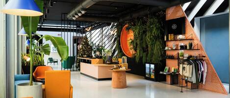 A modern interior with a reception desk, seating area, and a clothing rack.