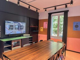 A conference room with a wooden table, chairs, a large screen, and motivational posters on the walls.