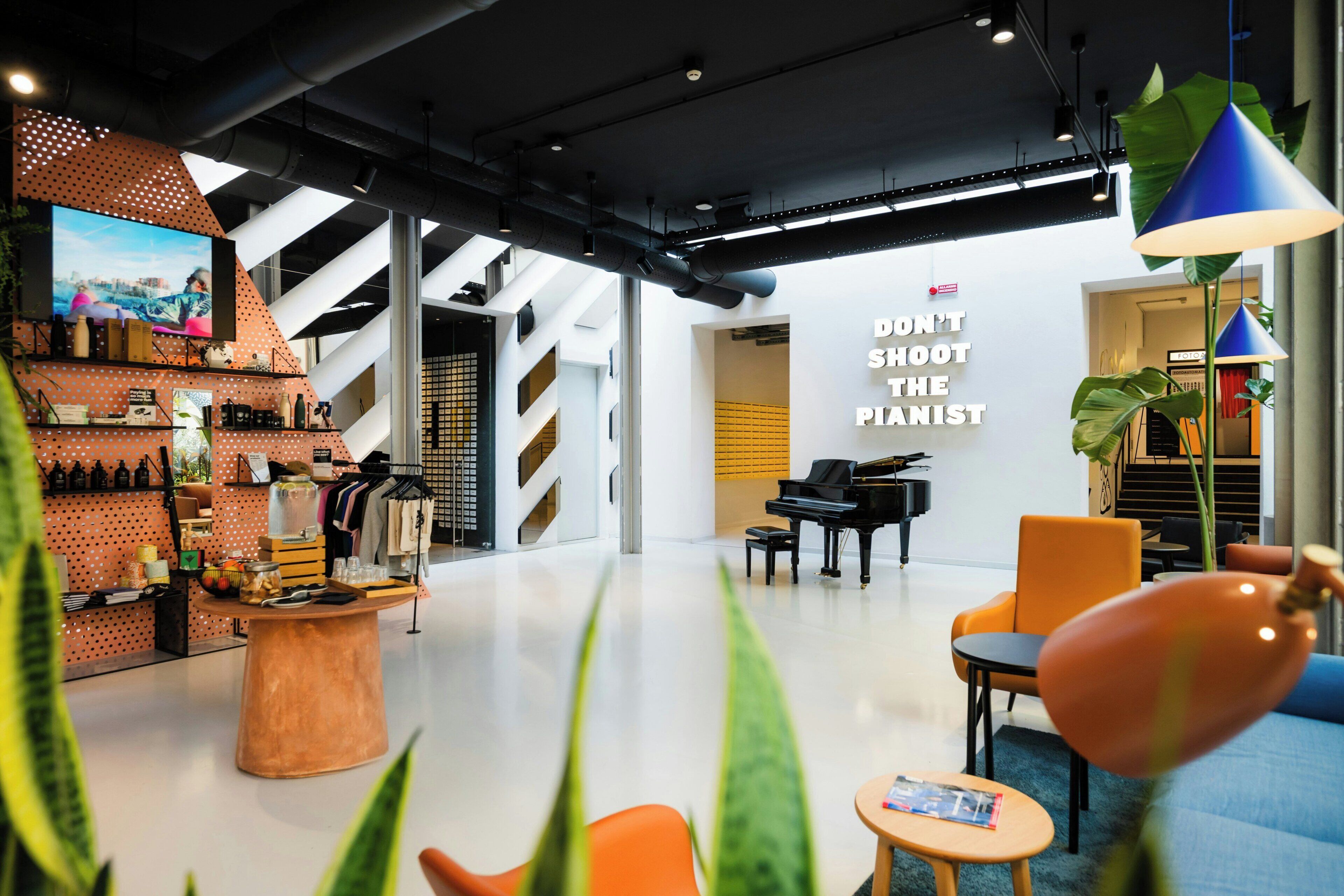 Un intérieur moderne avec un piano, un coin salon et un mur orné d’une citation inspirante.