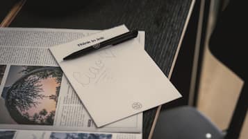 A desk with a notebook, a pen, and a newspaper.