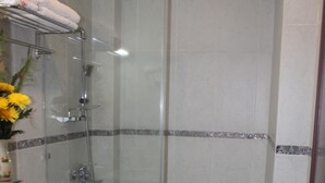 A bathroom with a glass-enclosed shower, a toilet, a sink, and a towel rack with towels.