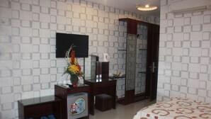 A hotel room with a bed, a desk with a computer, a television, and a wardrobe.