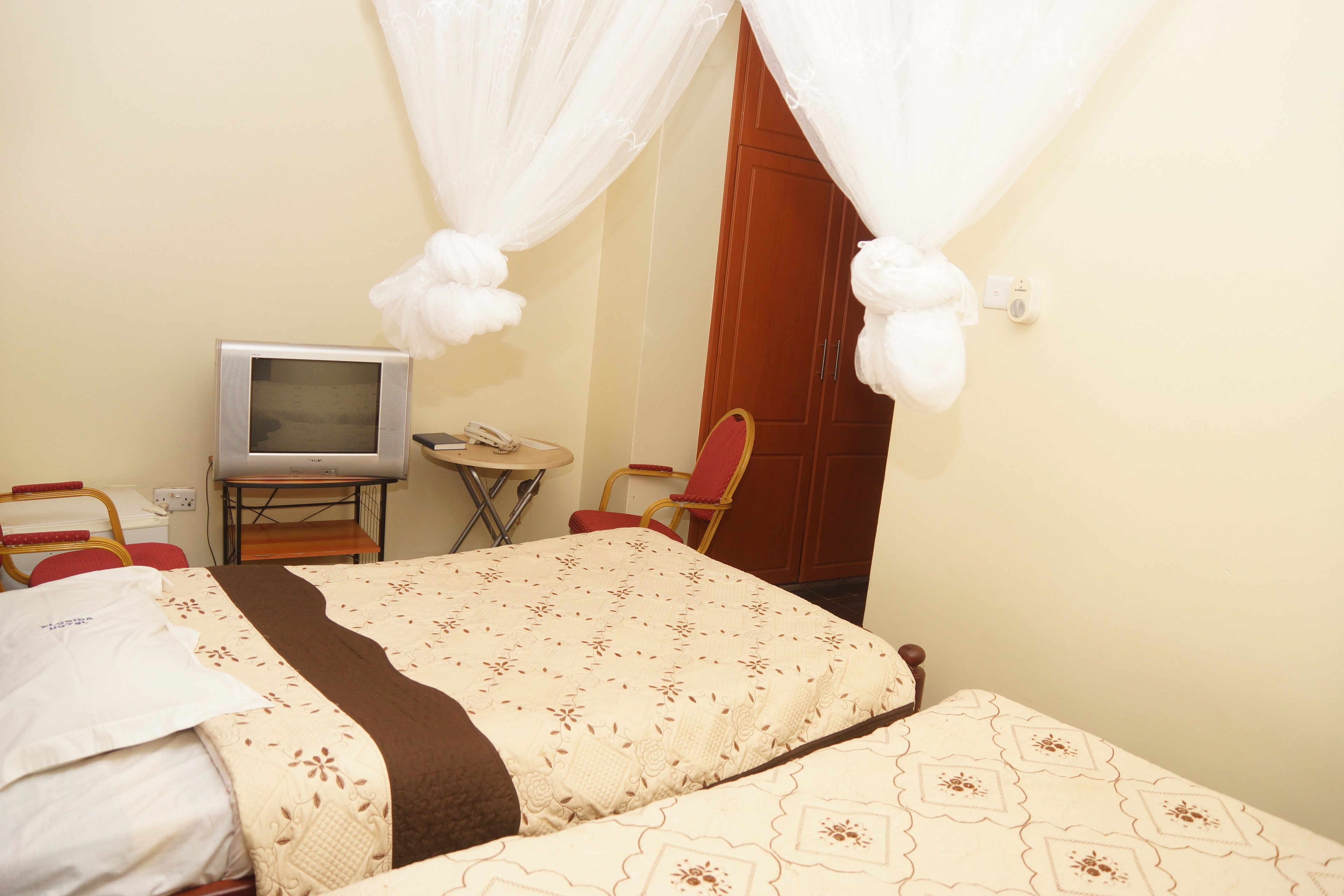 A hotel room with two beds, a television, a small table, and a red chair.