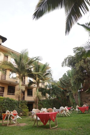 Un patio con mobiliario exterior, palmeras y un edificio con varios balcones.