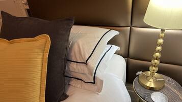 A neatly made bed with multiple pillows and a bedside table with a lamp.