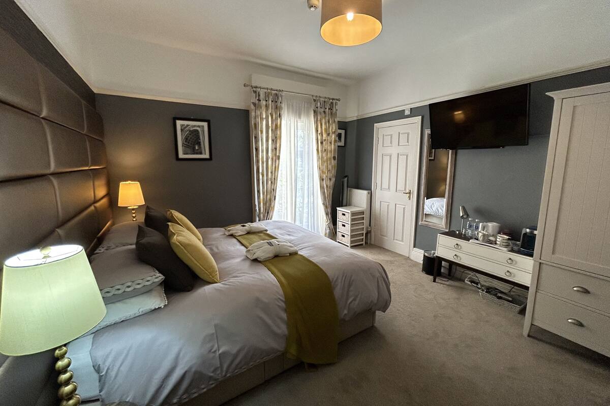 A bedroom with a bed, bedside lamps, a television, a wardrobe, and a door.