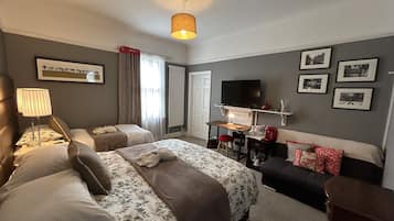 Habitación de hotel con dos camas, televisión, escritorio con lámpara y cuadros en la pared.