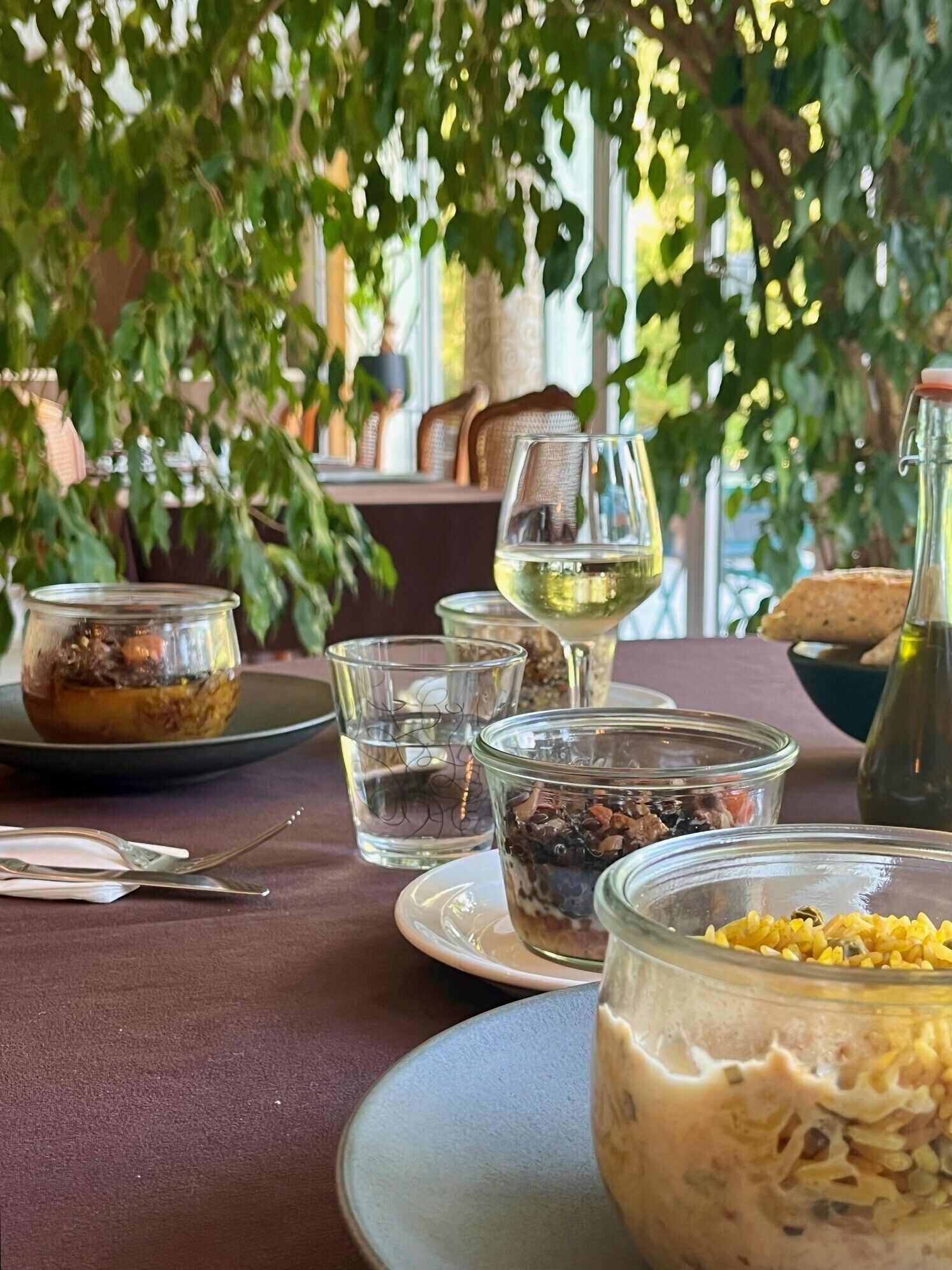 Una mesa servida con distintos platos, vasos y una botella, probablemente en un restaurante o cafetería.