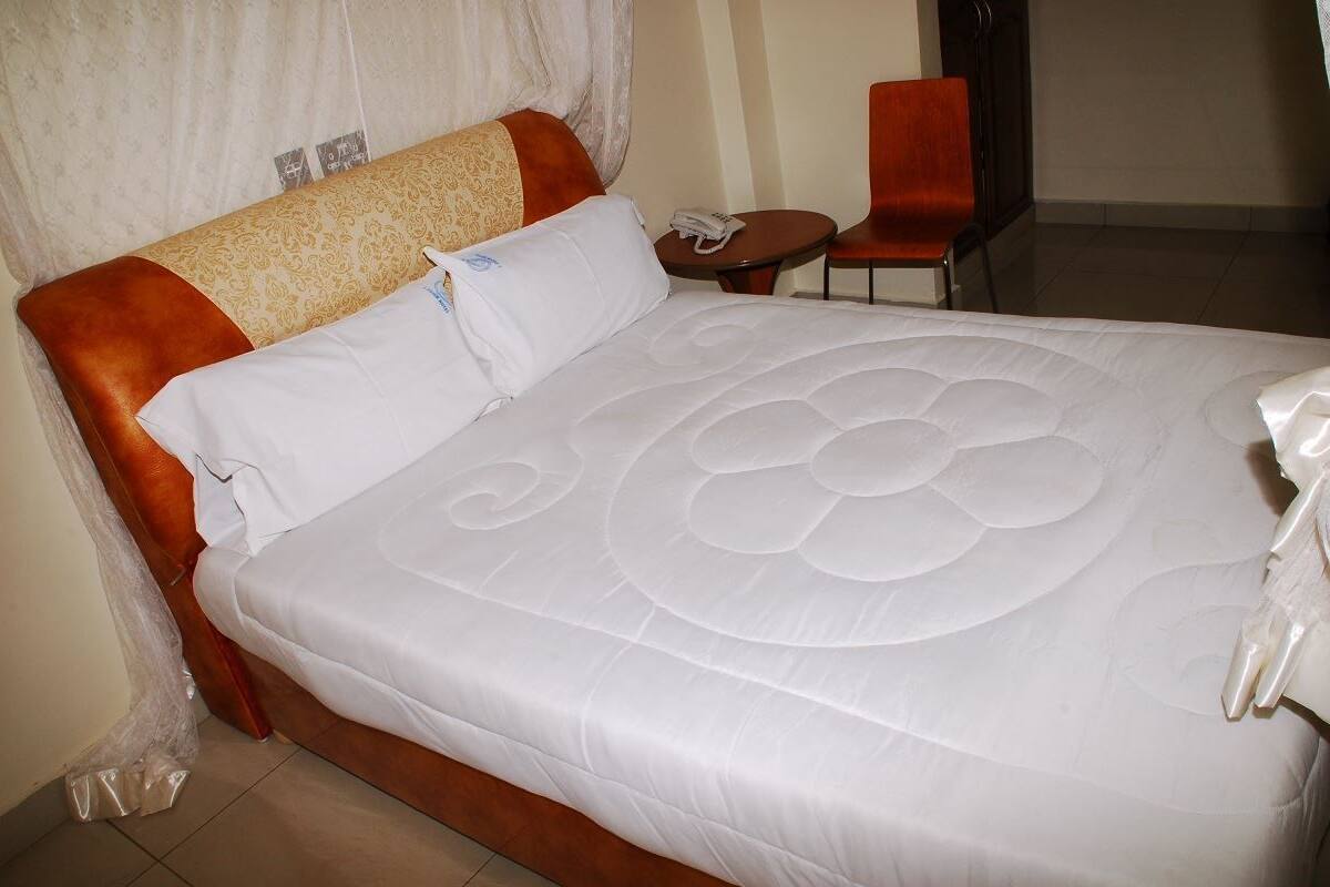 Una habitación de hotel con una cama grande, una mesita redonda y una silla roja.