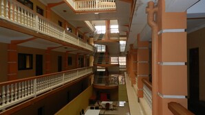 A multi-level atrium with a central open space, balconies, and a dining area with tables and chairs. - Hotel Jfrigh (Kampala)