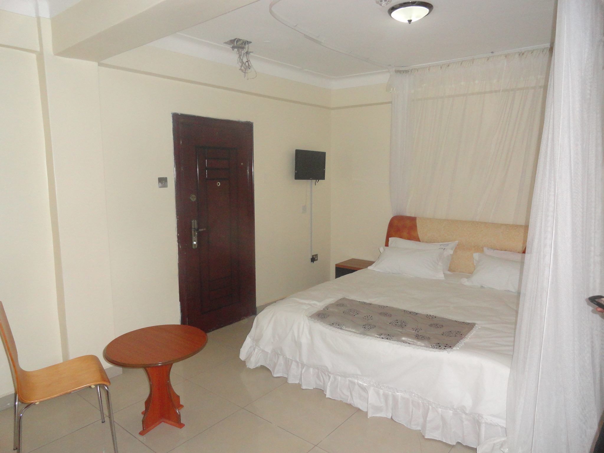 A hotel room with a bed, a TV, a chair, and a table.