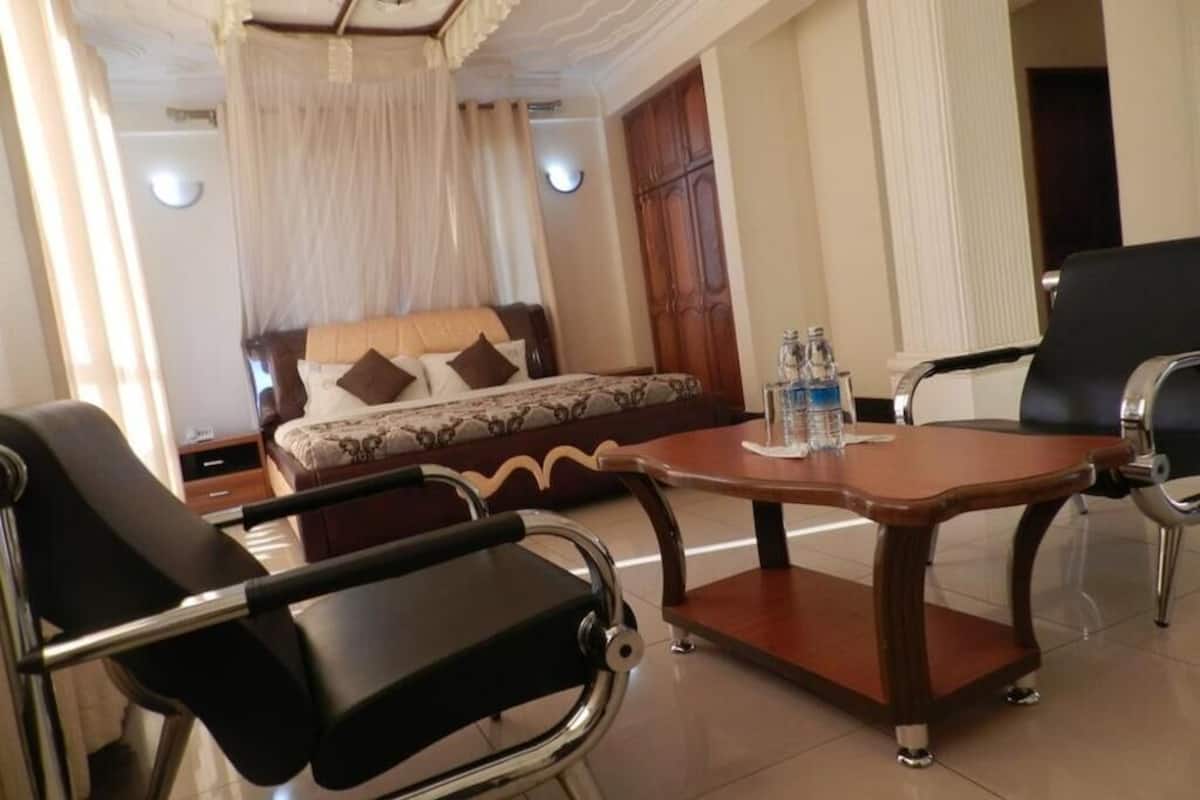 Una habitación de hotel con una cama, una mesa redonda de madera y sillas, y un armario.