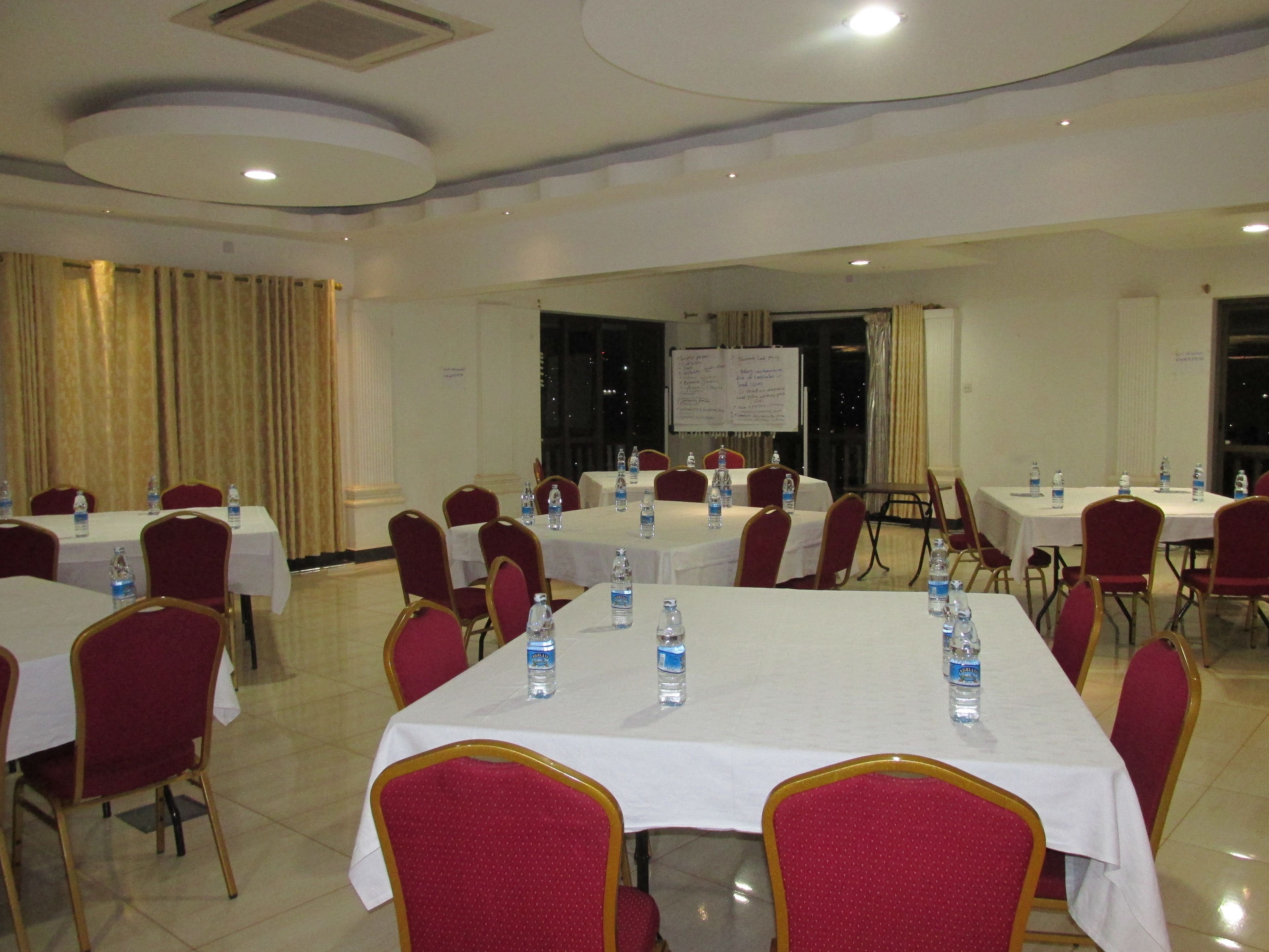 A conference room with tables set for meetings, equipped with water bottles, and red chairs.