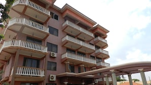 A multi-story hotel with balconies, air conditioning units, and a covered entrance. - Hotel Jfrigh (Kampala)