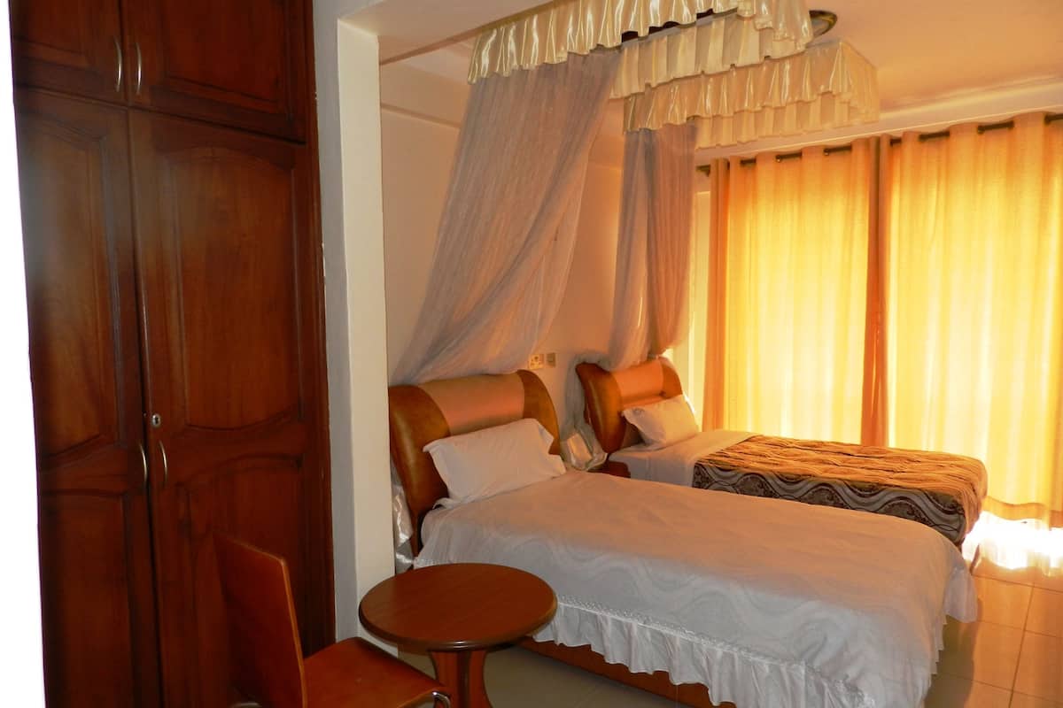 Una habitación de hotel con dos camas, un armario de madera, una mesa redonda y una cama con dosel.