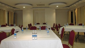 A conference room with tables and chairs, water bottles on each table, and a white ceiling with recessed lighting. - Hotel Jfrigh (Kampala)