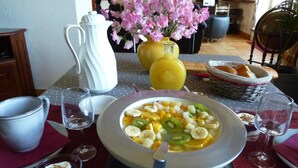 A breakfast setting with a fruit bowl, a pitcher, and a vase of flowers on a table.