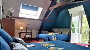 A bedroom with two beds, a desk, a chair, and a skylight.