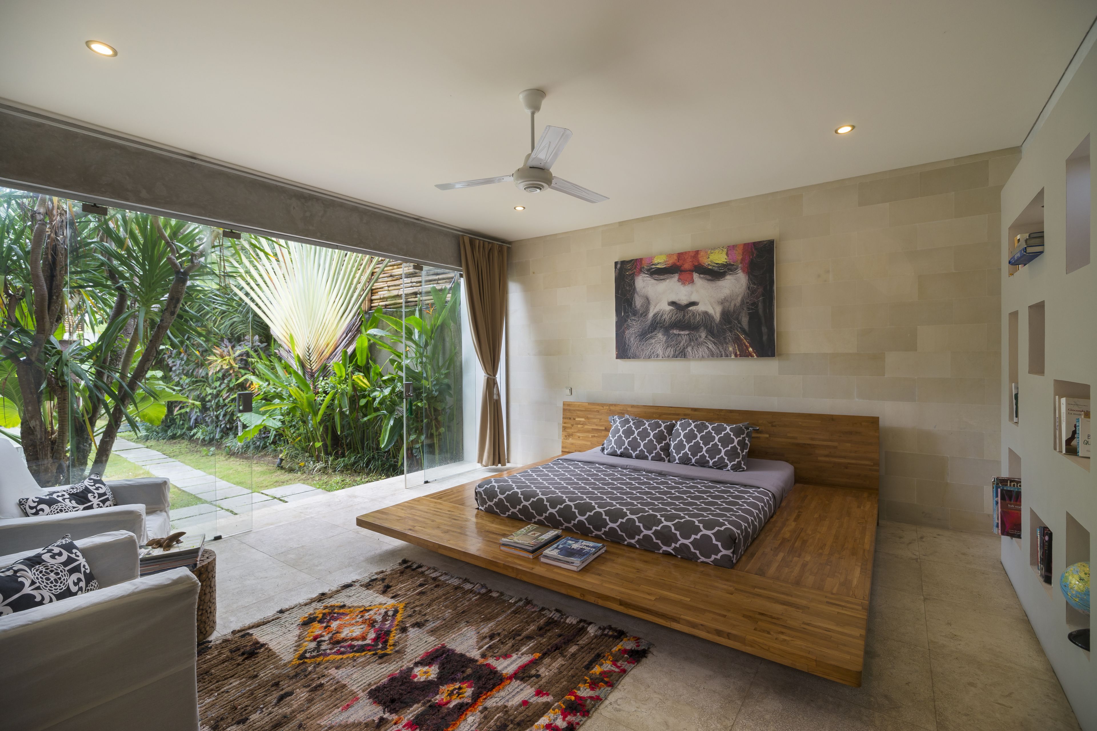 A modern bedroom with a floating bed, a ceiling fan, and a large window overlooking a garden.