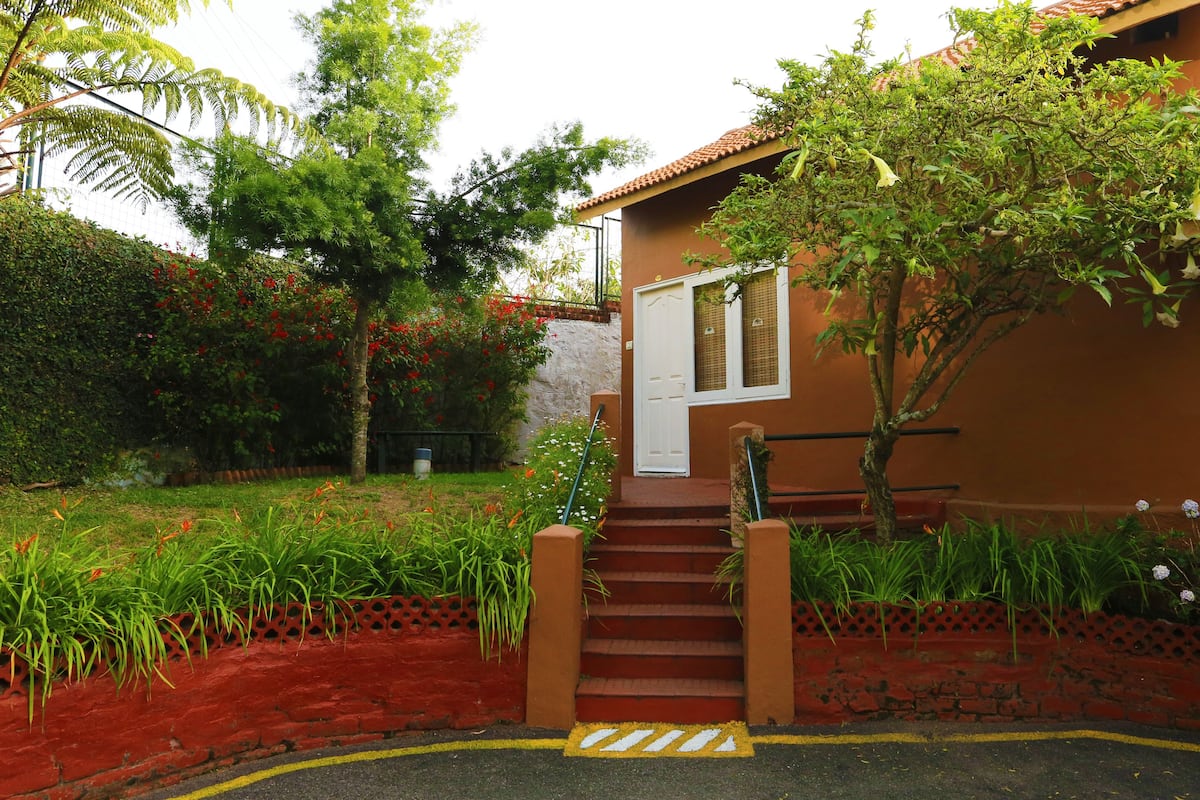 Una escalera que conduce a una puerta, rodeada de exuberante follaje y plantas en flor.