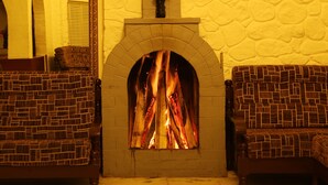 Una chimenea con arco de ladrillo, flanqueada por dos sillones tapizados con un diseño tejido.