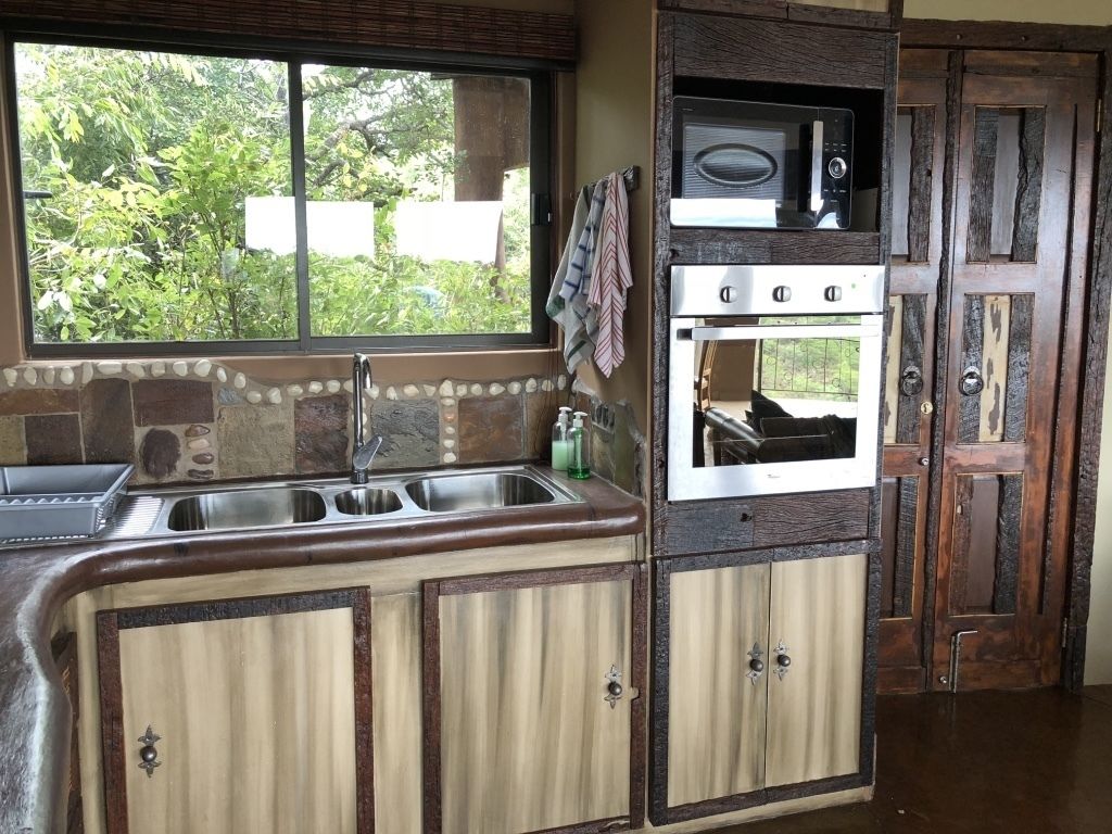 A kitchen with a window, a sink, a microwave, and an oven.