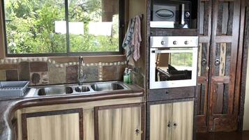 A kitchen with a window, a sink, a microwave, and an oven.