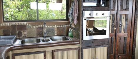 A kitchen with a window, a sink, a microwave, and an oven.