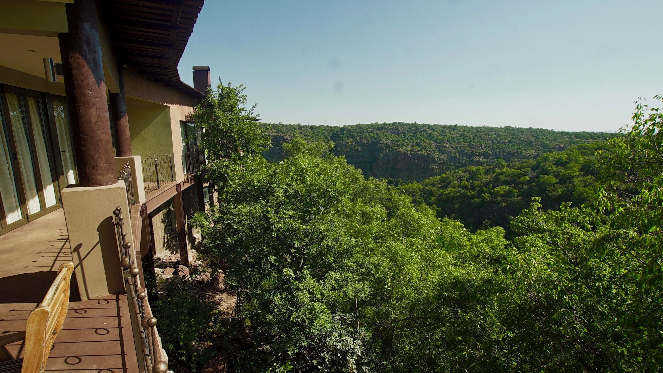 A building with a balcony overlooking a dense forest.