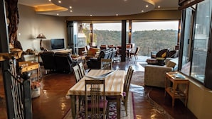Un vaste espace de vie comprenant une grande table à manger, des sièges confortables et une vue sur un paysage montagneux grâce à de grandes fenêtres.