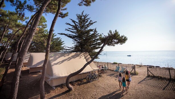 A campsite with tents and bicycles, overlooking a beach and the sea. - Huttopia Noirmoutier (Noirmoutier-en-l'Ile)