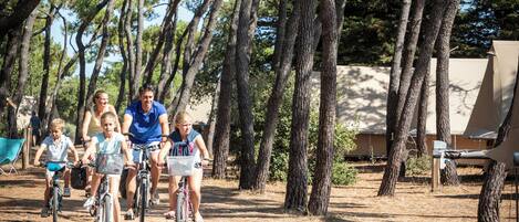 A group of people riding bicycles on a dirt path surrounded by trees.