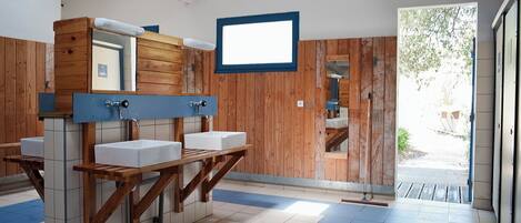 A public restroom with wooden partitions, multiple sinks, and a large mirror.