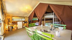 A compact kitchen with a refrigerator, sink, and dining area with green chairs and a table. - Huttopia Noirmoutier (Noirmoutier-en-l'Ile)
