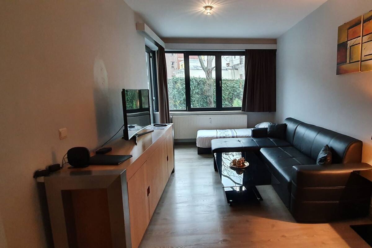 Una sala moderna con sofá, una mesa de centro, televisor y comedor.