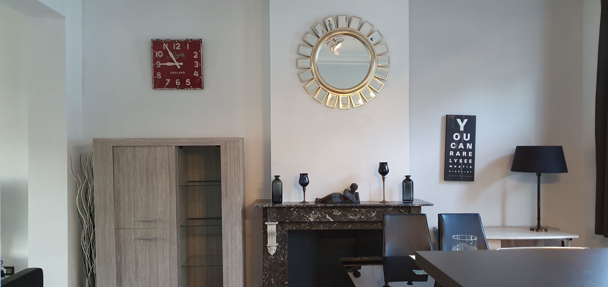 Un salon moderne avec une cheminée, un miroir rond, une horloge et une affiche motivante.