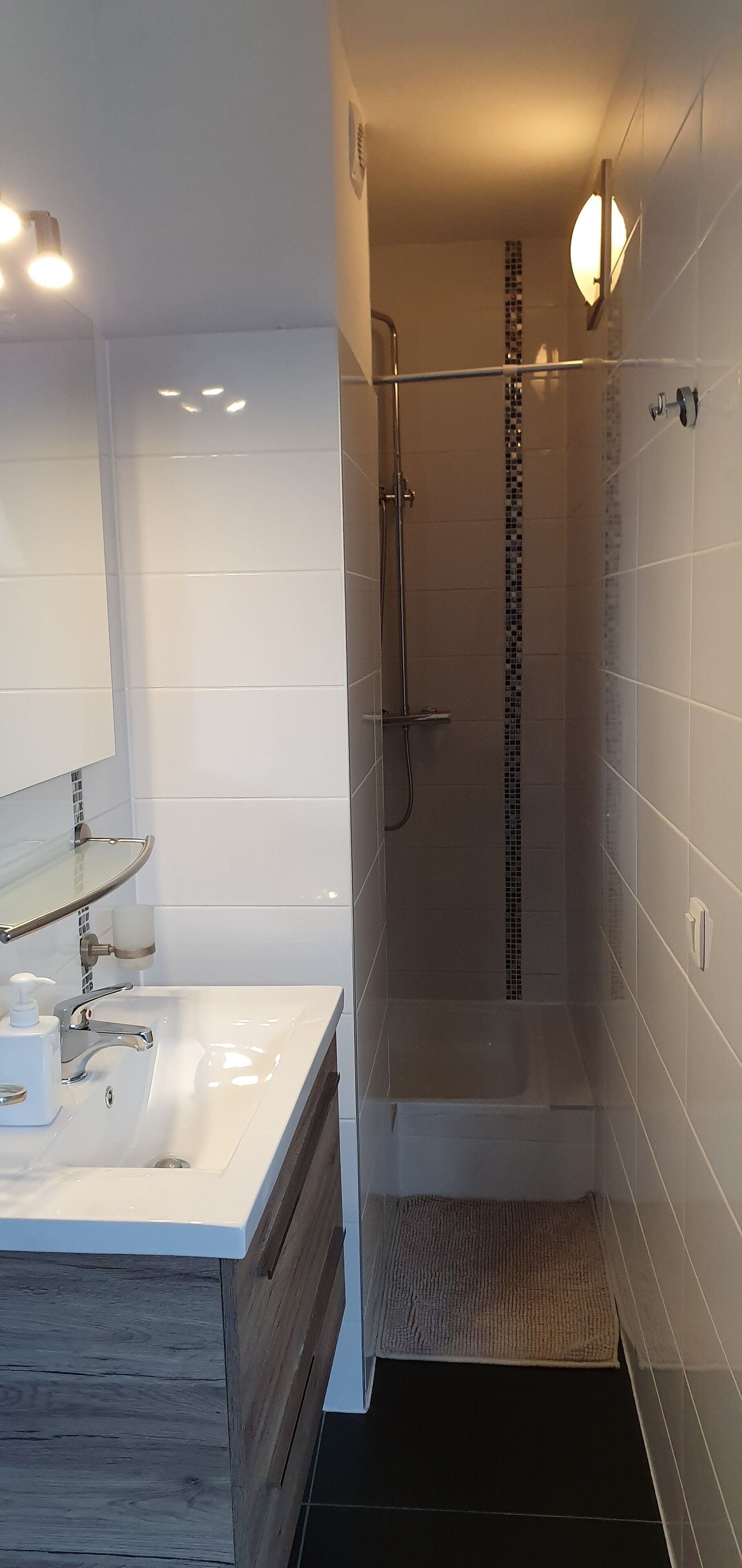 A modern bathroom with a white vanity, a glass shower enclosure, and a tiled floor.