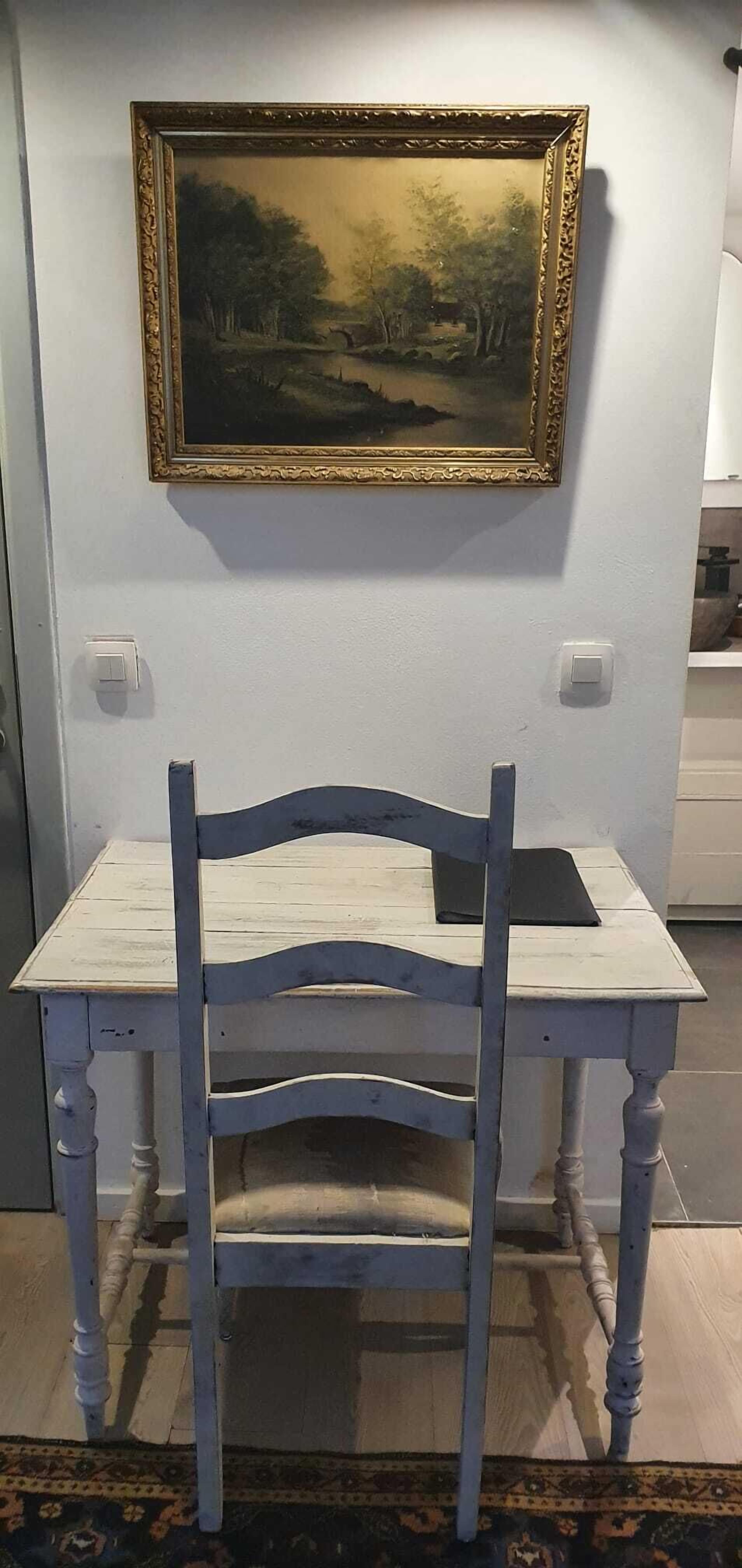 Ein weißer Tisch mit einem blauen Stuhl vor einer Wandmalerei.