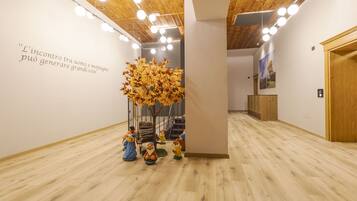 Un corridoio con pavimento in legno, una scultura di un albero e una scala.