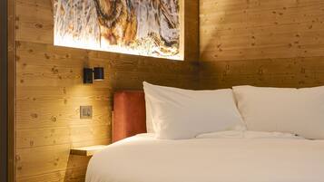 Ein Schlafzimmer mit Holz-Kopfteil, einem großen Gemälde eines Wolfs, einer roten Akzentwand und einem runden Bett mit weißer Bettwäsche.