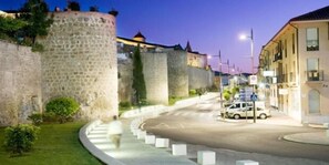 Una calle con una glorieta, muros de piedra y edificios modernos.