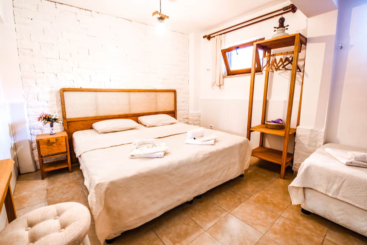 Una habitación con una cama grande, un armario de madera, una mesita con una lámpara y una silla.