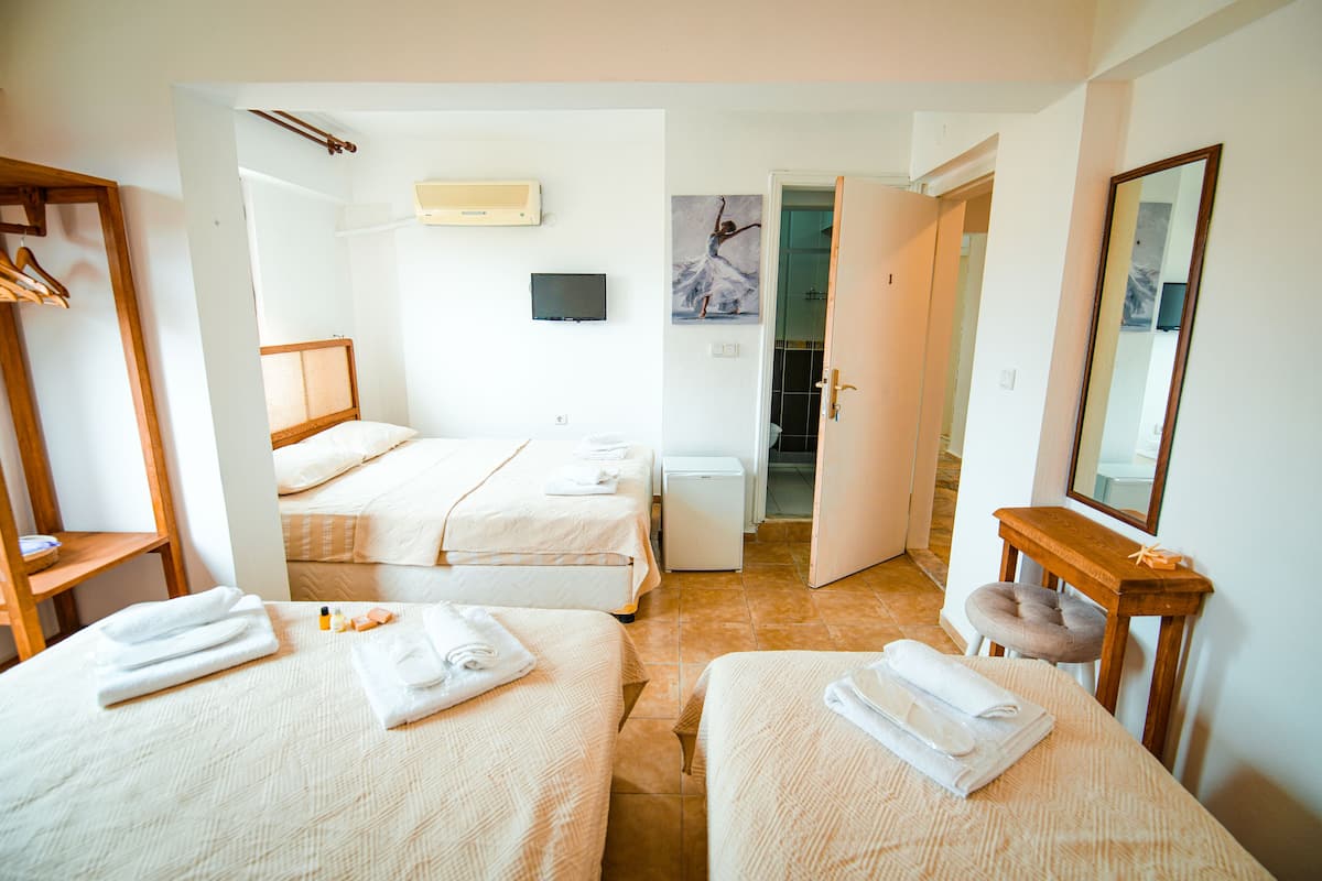 Habitación de hotel con dos camas, un escritorio pequeño, un espejo y una puerta que da a un baño.