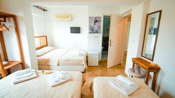 A hotel room with two beds, a small desk, a mirror, and a door leading to a bathroom.