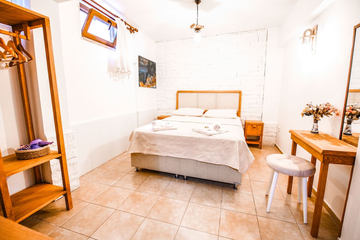Un dormitorio con una cama, un aparador de madera, un tocador con espejo y una ventana con vistas al exterior.