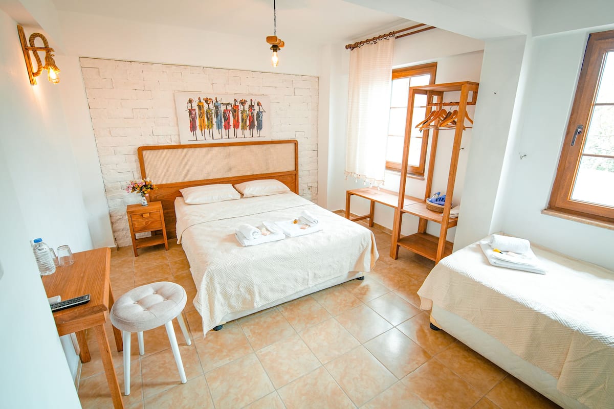 Un dormitorio con cama, escritorio, silla, perchero y ventana.