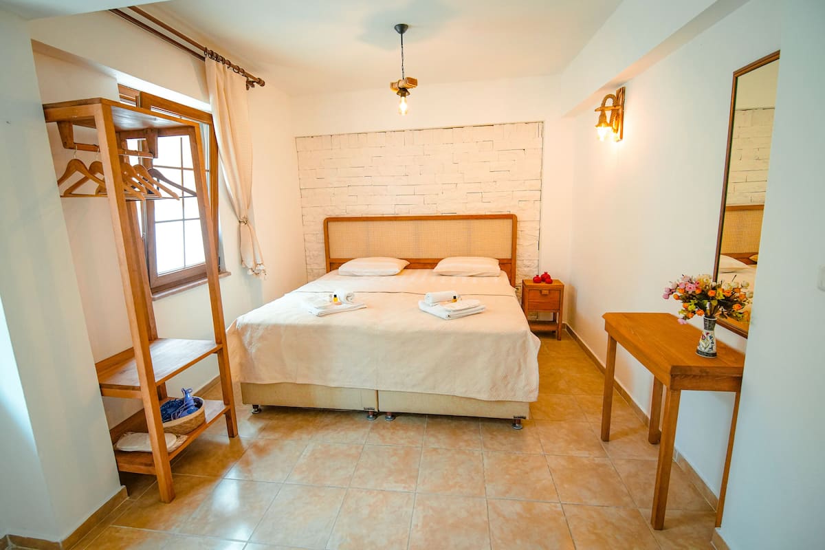Un dormitorio con cama, armario de madera, mesita de noche y un espejo.