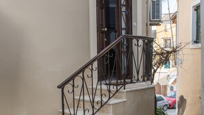 Eine steinerne Treppe führt zu einer Tür mit einem schmiedeeisernen Geländer.