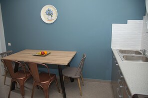 A kitchen with a wooden table, two brown chairs, a white sink, and a blue wall.